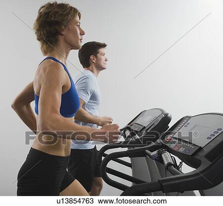 Couple running on treadmills View Large Photo Image Stock Image - Couple running on treadmills. Fotosearch
