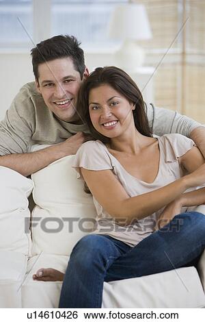 Couple sitting on sofa View Large Photo Image Stock Photograph - Couple sitting on sofa. Fotosearch