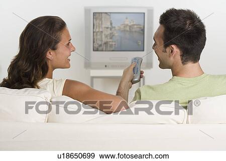 Couple sitting on sofa watching television View Large Photo Image Stock Photo - Couple sitting on sofa watching television. Fotosearch