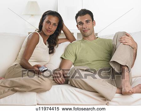 Couple sitting on sofa watching television View Large Photo Image Stock Photography - Couple sitting on sofa watching television. Fotosearch