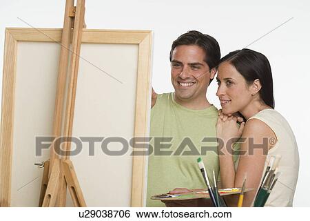 Couple smiling and looking at easel View Large Photo Image Stock Photograph - Couple smiling and looking at easel. Fotosearch