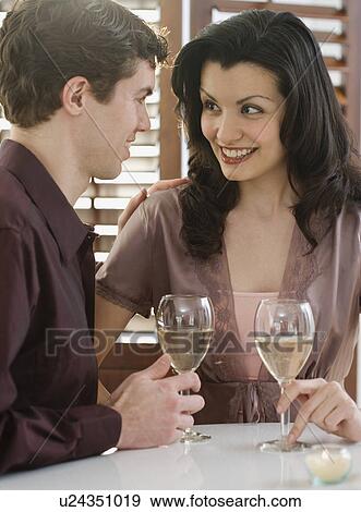 Stock Photo - Couple smiling at each other at restaurant. Fotosearch