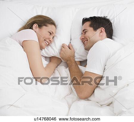 Stock Photograph - Couple smiling at each other in bed. Fotosearch