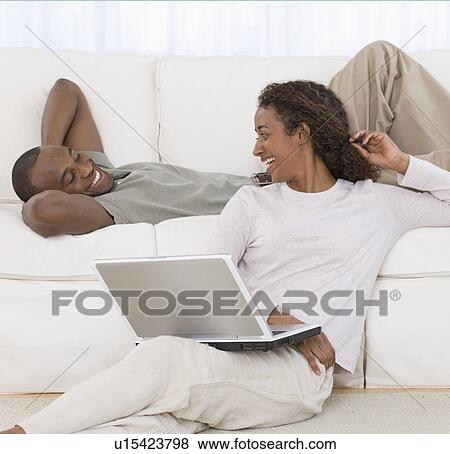 Couple smiling at each other in livingroom View Large Photo Image Stock Photo - Couple smiling at each other in livingroom. Fotosearch