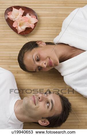 Stock Image - Couple smiling at each other while laying on floor. Fotosearch