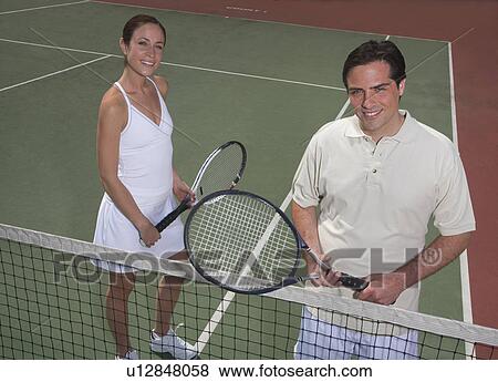 Stock Photo - Couple smiling on tennis court. Fotosearch