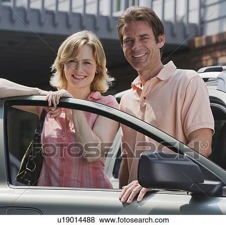 Couple standing in car door View Large Photo Image Stock Photo - Couple standing in car door. Fotosearch