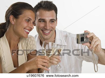Stock Photograph - Couple talking own photograph while toasting with wine. Fotosearch