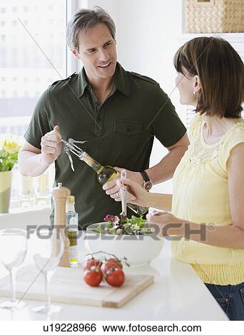 Couple tossing salad and opening wine View Large Photo Image Stock Photograph - Couple tossing salad and opening wine. Fotosearch