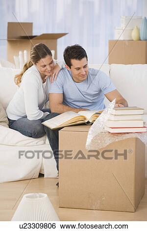 Couple unpacking books in new house View Large Photo Image Stock Photograph - Couple unpacking books in new house. Fotosearch