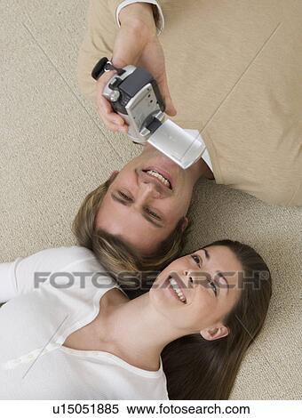 Stock Photography - Couple video recording themselves on floor. Fotosearch