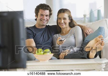Couple watching television on sofa View Large Photo Image Stock Photo - Couple watching television on sofa. Fotosearch