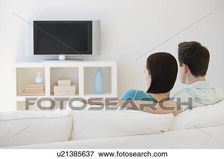 Stock Photo - Couple watching television on sofa. Fotosearch