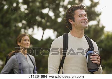 Picture - Couple wearing backpacks in woods. Fotosearch