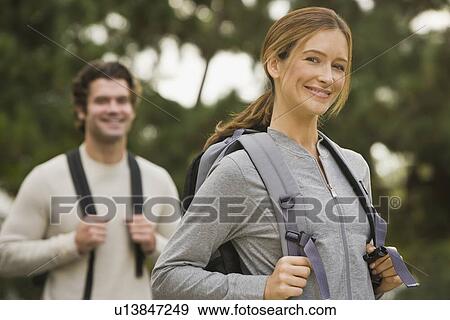 Stock Photo - Couple wearing backpacks in woods. Fotosearch