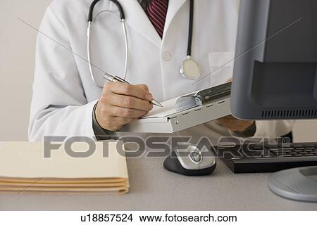 Doctor writing on chart at desk View Large Photo Image Picture - Doctor writing on chart at desk. Fotosearch
