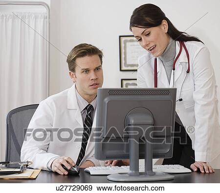 Doctors looking at computer in office View Large Photo Image Stock Photo - Doctors looking at computer in office. Fotosearch