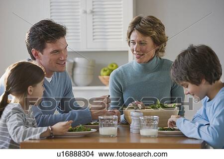 Picture - Family eating at dinner table. Fotosearch