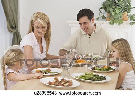 Stock Image - Family eating at dinner table. Fotosearch