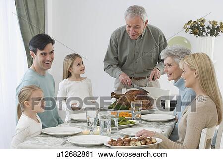Stock Image - Family eating at Thanksgiving table. Fotosearch
