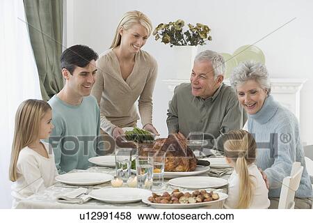 Stock Photo - Family eating at Thanksgiving table. Fotosearch