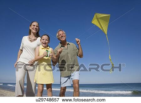 Stock Photo - Family flying kite at beach. Fotosearch