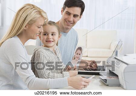 Stock Photography - Family printing pictures with laptop. Fotosearch