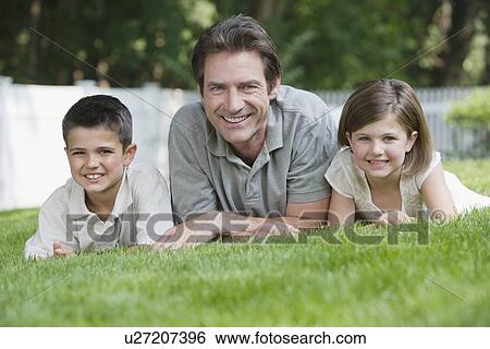 Father and children laying in grass View Large Photo Image Stock Photograph - Father and children laying in grass. Fotosearch