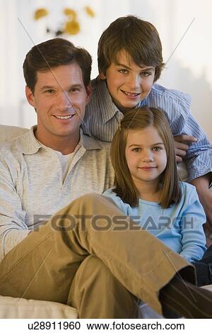 Stock Image - Father and children sitting on sofa. Fotosearch