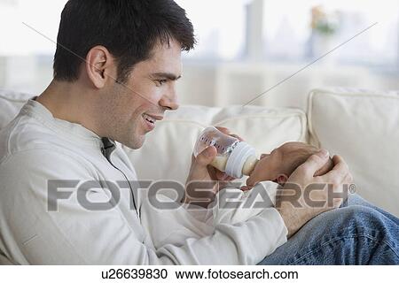 Father feeding newborn baby on sofa View Large Photo Image Stock Image - Father feeding newborn baby on sofa. Fotosearch