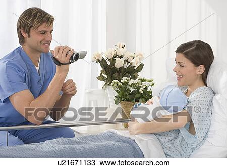 Stock Image - Father video recording mother and newborn baby. Fotosearch