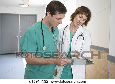 Stock Image - Female and male doctors discussing chart. Fotosearch