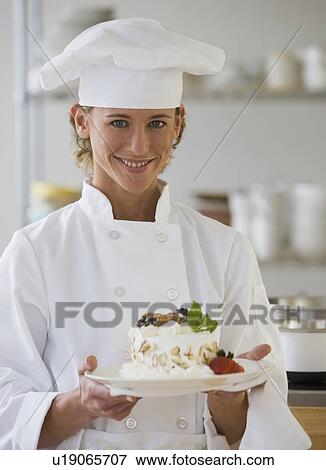 Stock Photo - Female chef holding plate of dessert. Fotosearch