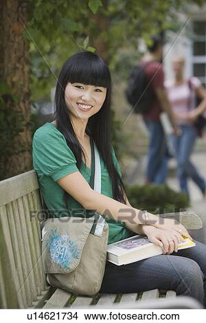 Female college student sitting on bench View Large Photo Image Picture - Female college student sitting on bench. Fotosearch
