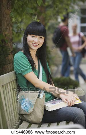 Female college student sitting on bench View Large Photo Image Stock Photograph - Female college student sitting on bench. Fotosearch