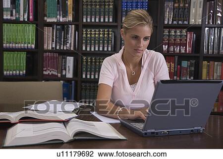 Stock Image - Female college student studying in library. Fotosearch