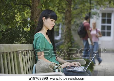 Stock Photograph - Female college student typing on laptop. Fotosearch