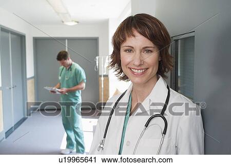 Female doctor leaning on wall View Large Photo Image Stock Image - Female doctor leaning on wall. Fotosearch
