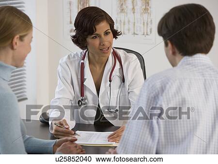 Female doctor talking to couple in office View Large Photo Image Stock Image - Female doctor talking to couple in office. Fotosearch