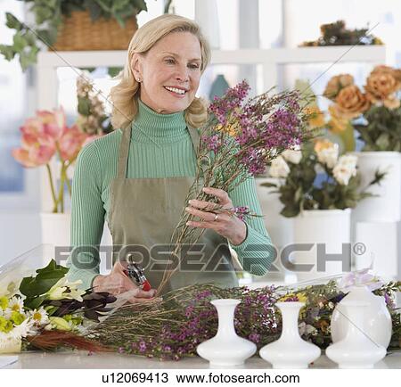 Stock Image - Female florist cutting flowers. Fotosearch