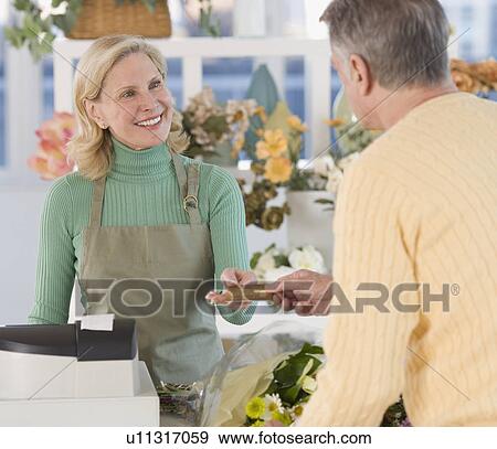 Stock Photo - Female florist ringing up customer. Fotosearch