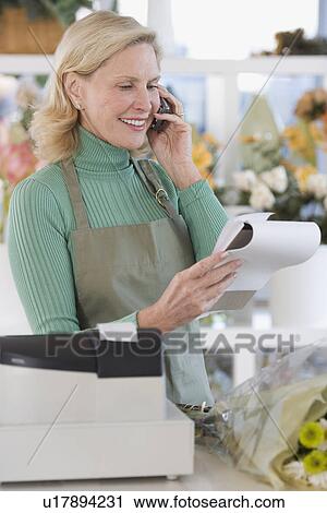 Stock Image - Female florist talking on telephone. Fotosearch