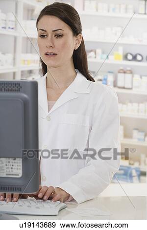 Stock Photo - Female pharmacist typing on computer. Fotosearch