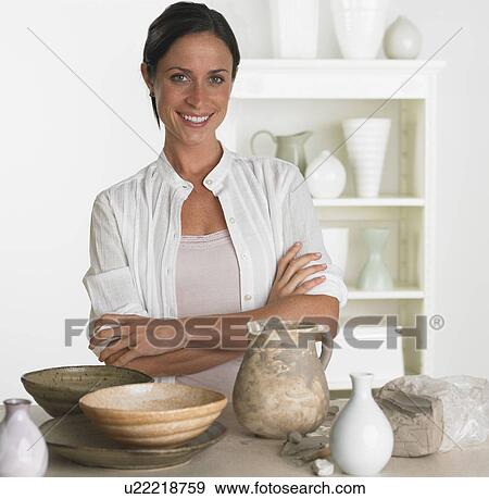Stock Photo - Female potter smiling next to pottery. Fotosearch