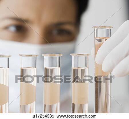 Stock Photography - Female scientist looking at vials of liquid. Fotosearch
