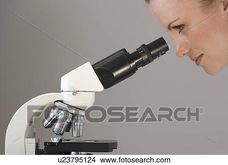 Picture - Female scientist looking in microscope. Fotosearch