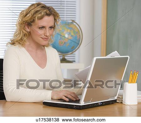 Stock Photo - Female teacher typing on laptop. Fotosearch