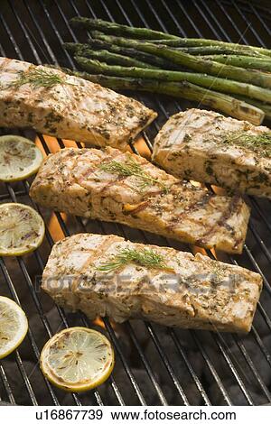 Stock Photo - Fish and asparagus cooking on grill. Fotosearch