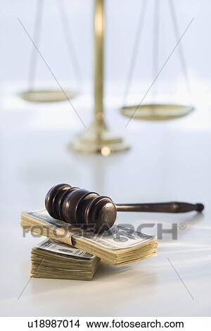 Picture - Gavel on stack of money with scales in background. Fotosearch