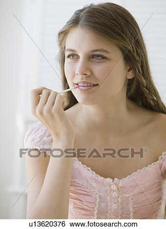 Stock Photograph - Girl applying lip gloss. Fotosearch